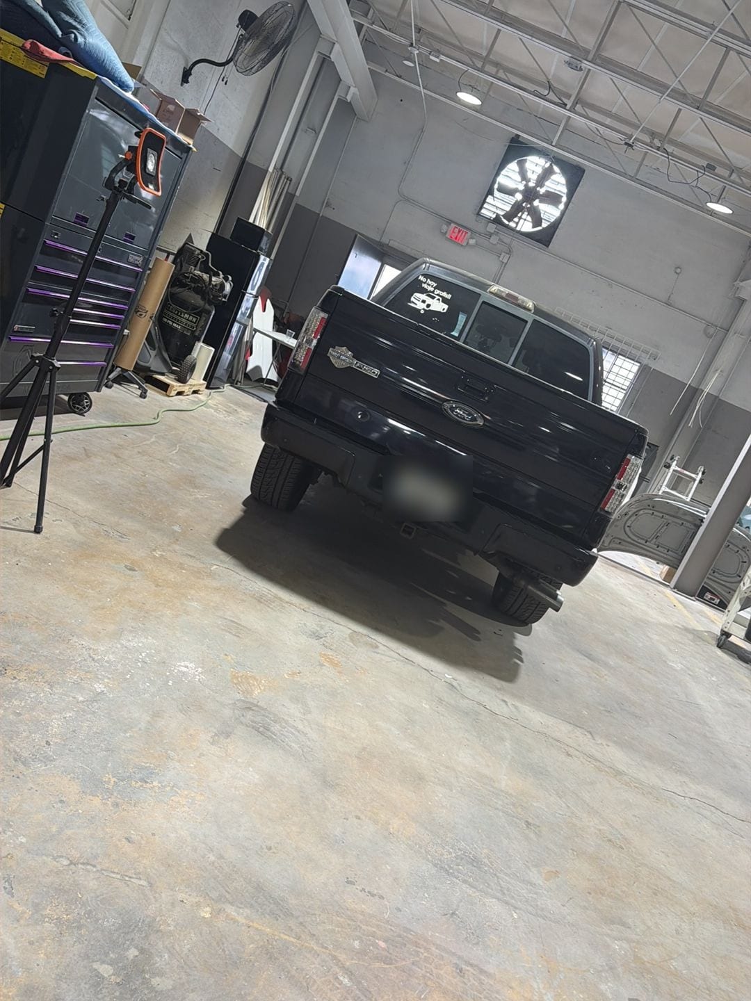 A black Ford pickup in a bay at ABE Auto Collision