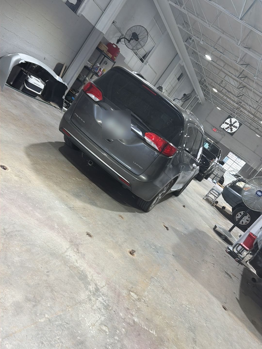 A gray minivan in the long white repair bay at ABE Auto Collision