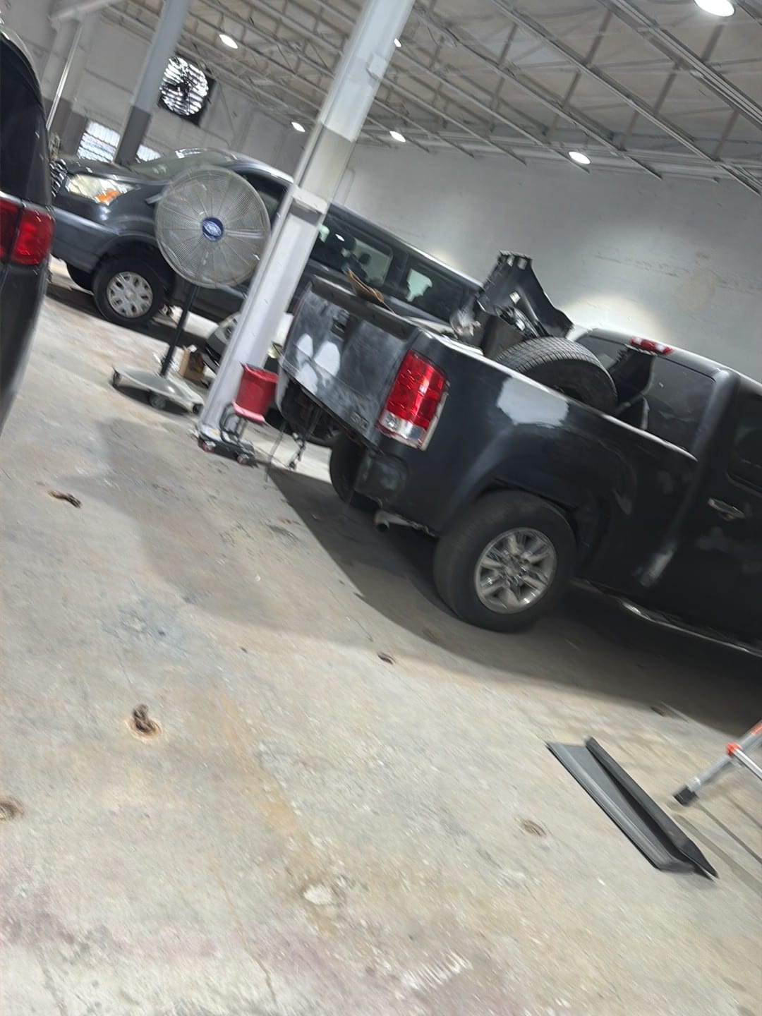 A pickup and a pedestal fan inside the repair bay at ABE Auto Collision