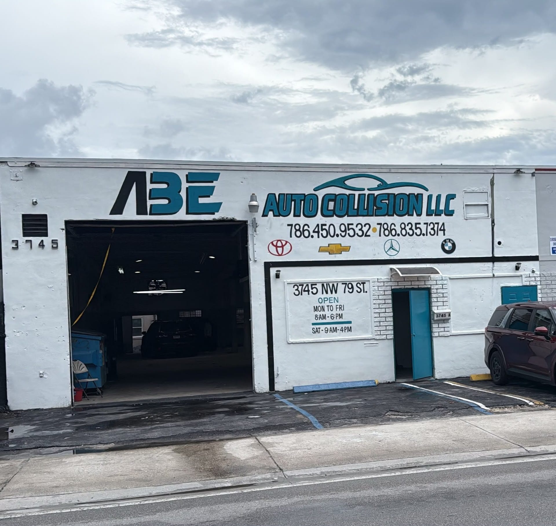 The ABE Auto Collision storefront with the painted logo and the teal door
